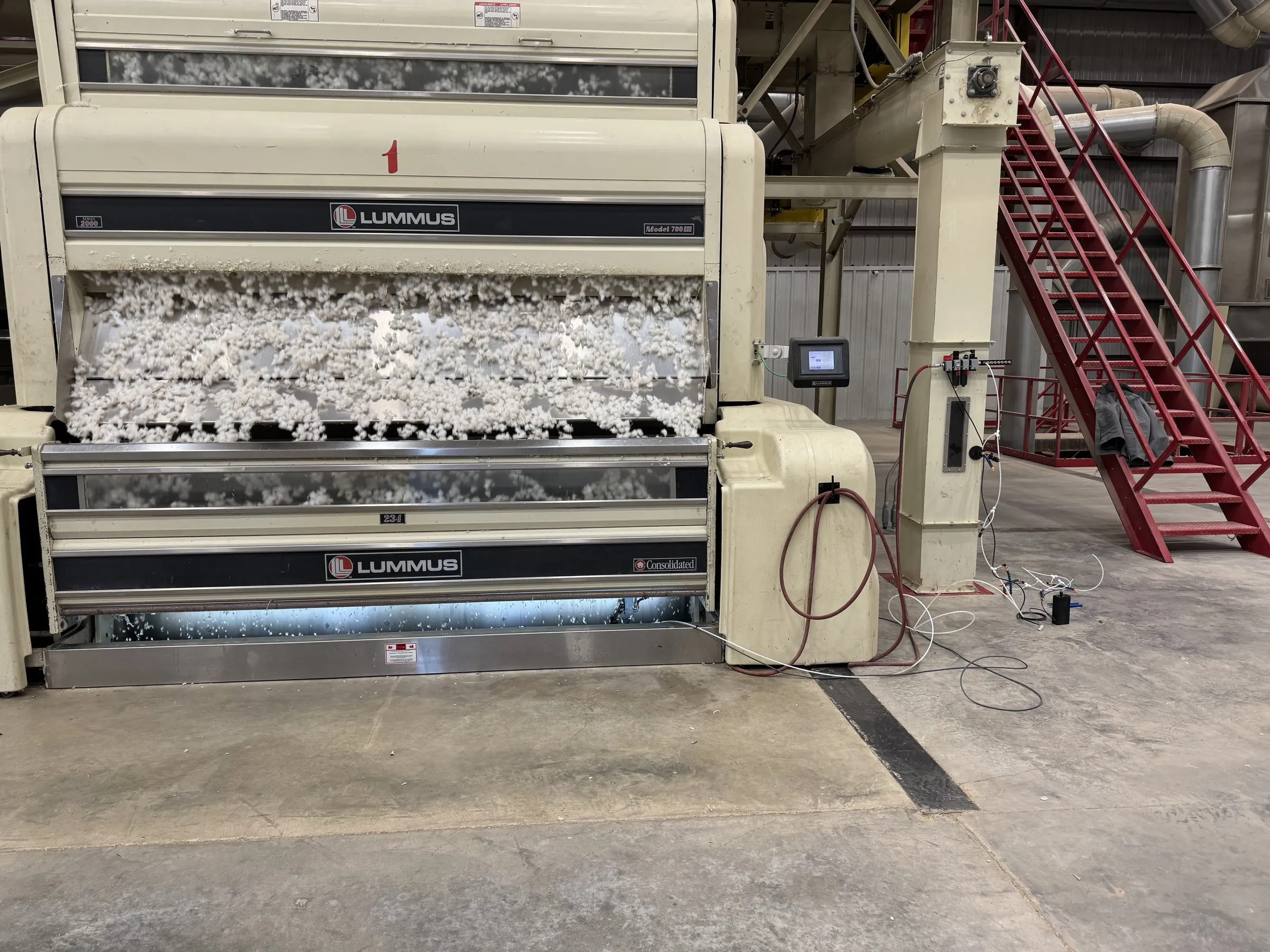 Seed cotton moving through a gin stand on the gin floor