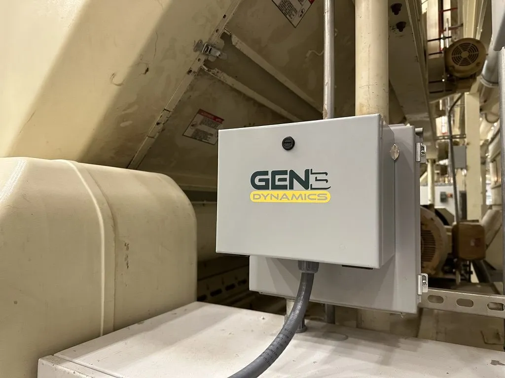 A white Gen 3 Dynamics enclosure bolted to the frame beside a gin stand, conduit running from its base into the machine